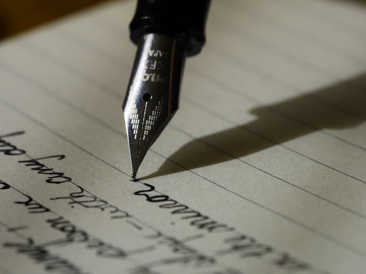 A pen resting on handwritten pages